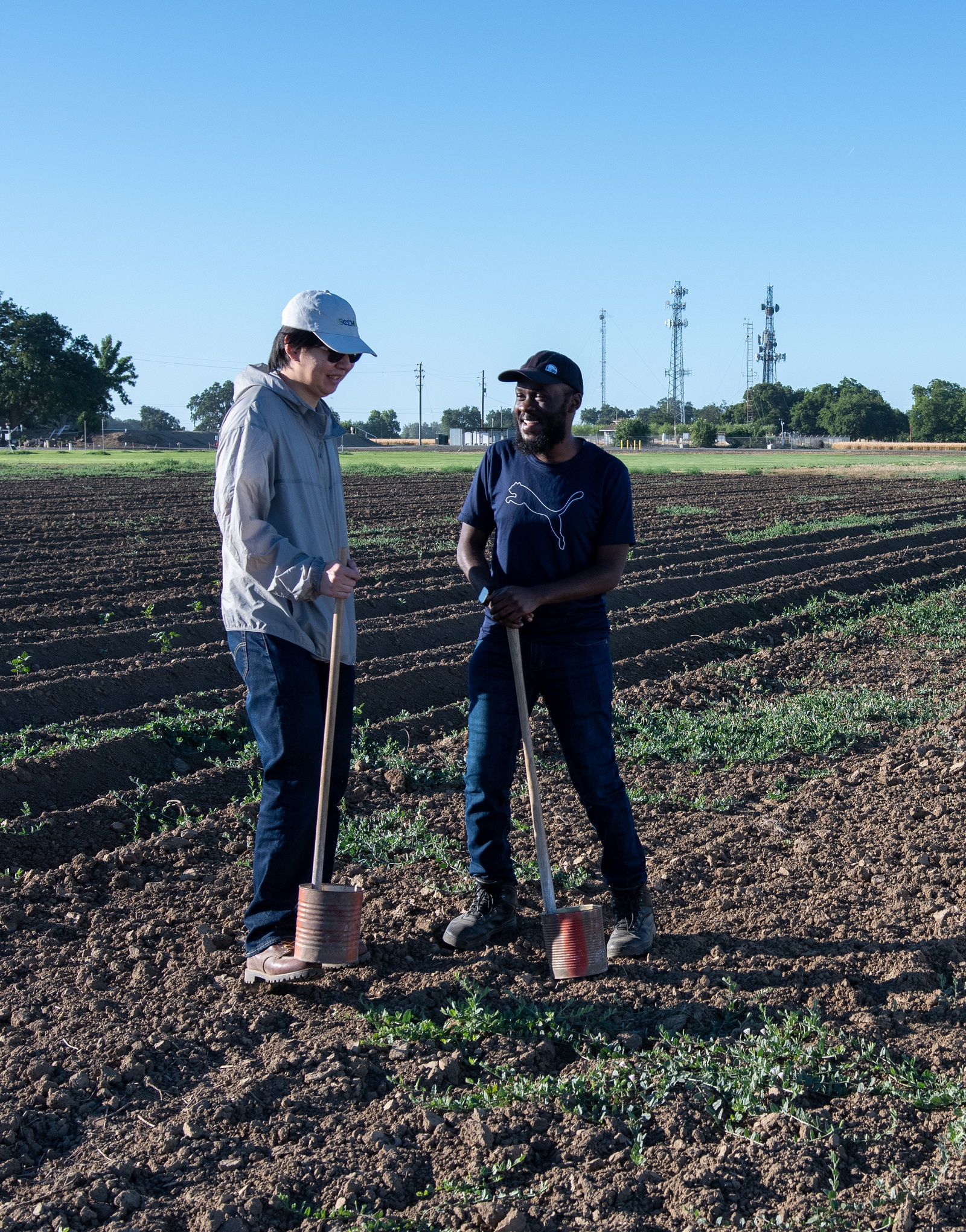Tong Lei (left) stands in the field with Ismael Mayanja